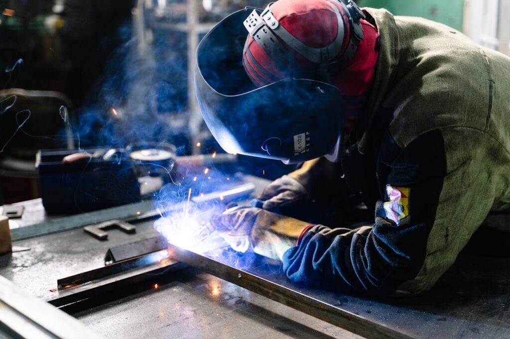 welding A welder works on metal fabrication indoors, creating bright sparks and smoke.